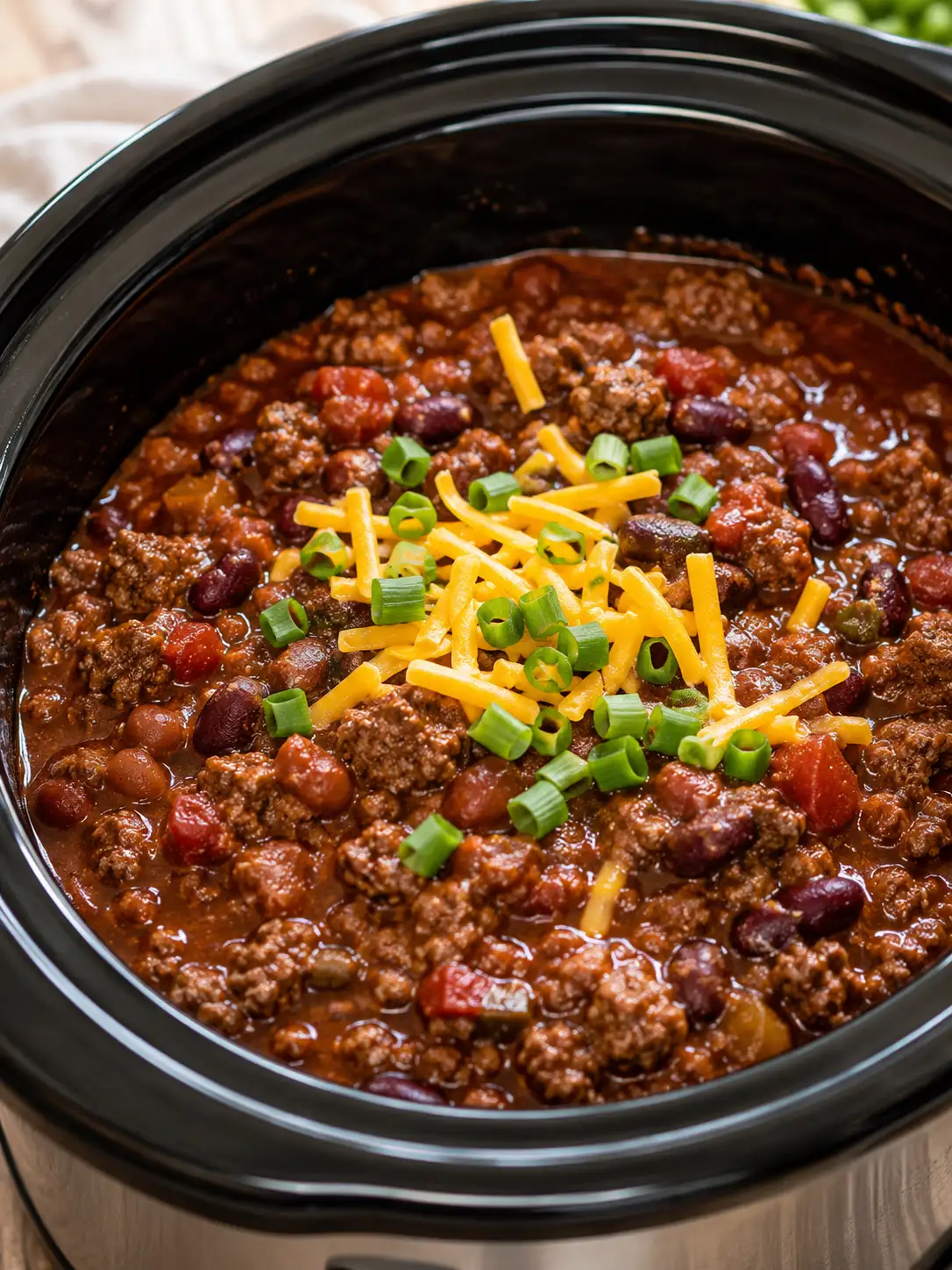Crockpot beef chili with beans, cheese, and green onion